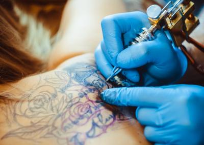 woman getting tattoo on her back